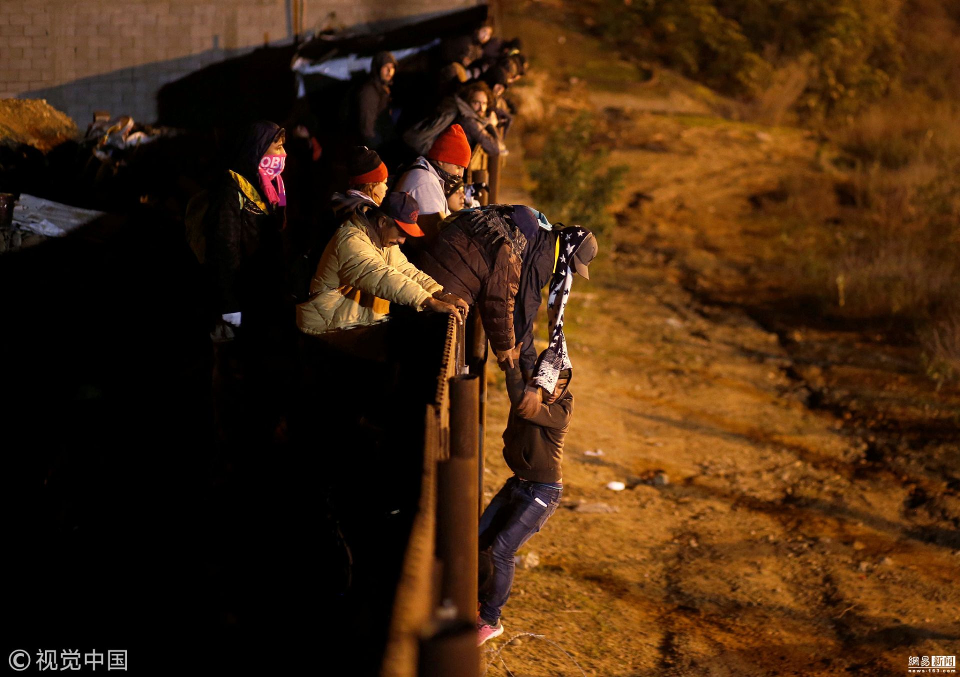 中美洲移民趁夜色翻越美墨边境墙 遭持枪警告