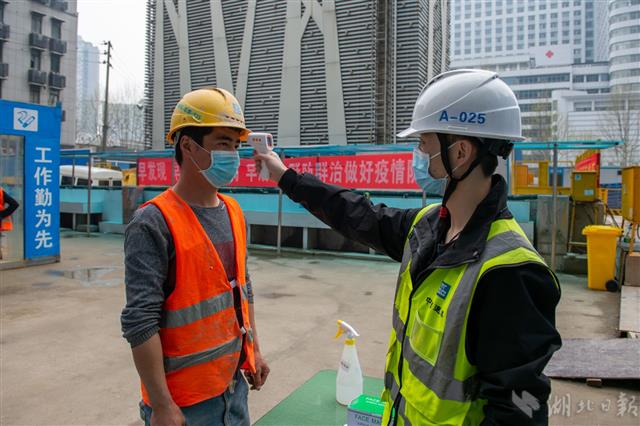 3月22日,武汉轨道交通8号线二期工程街道口站,工作人员测量体温.