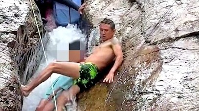男孩卡在小溪巨石縫里 男子跨坐石縫間拽出孩子