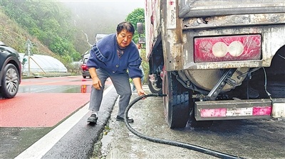 路上货车突然冒烟 她从家中拉出水管